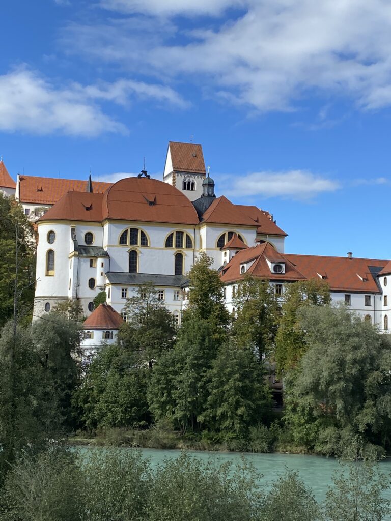 Large white structure with clay colored roof, once an abbey in Fussen, Germany