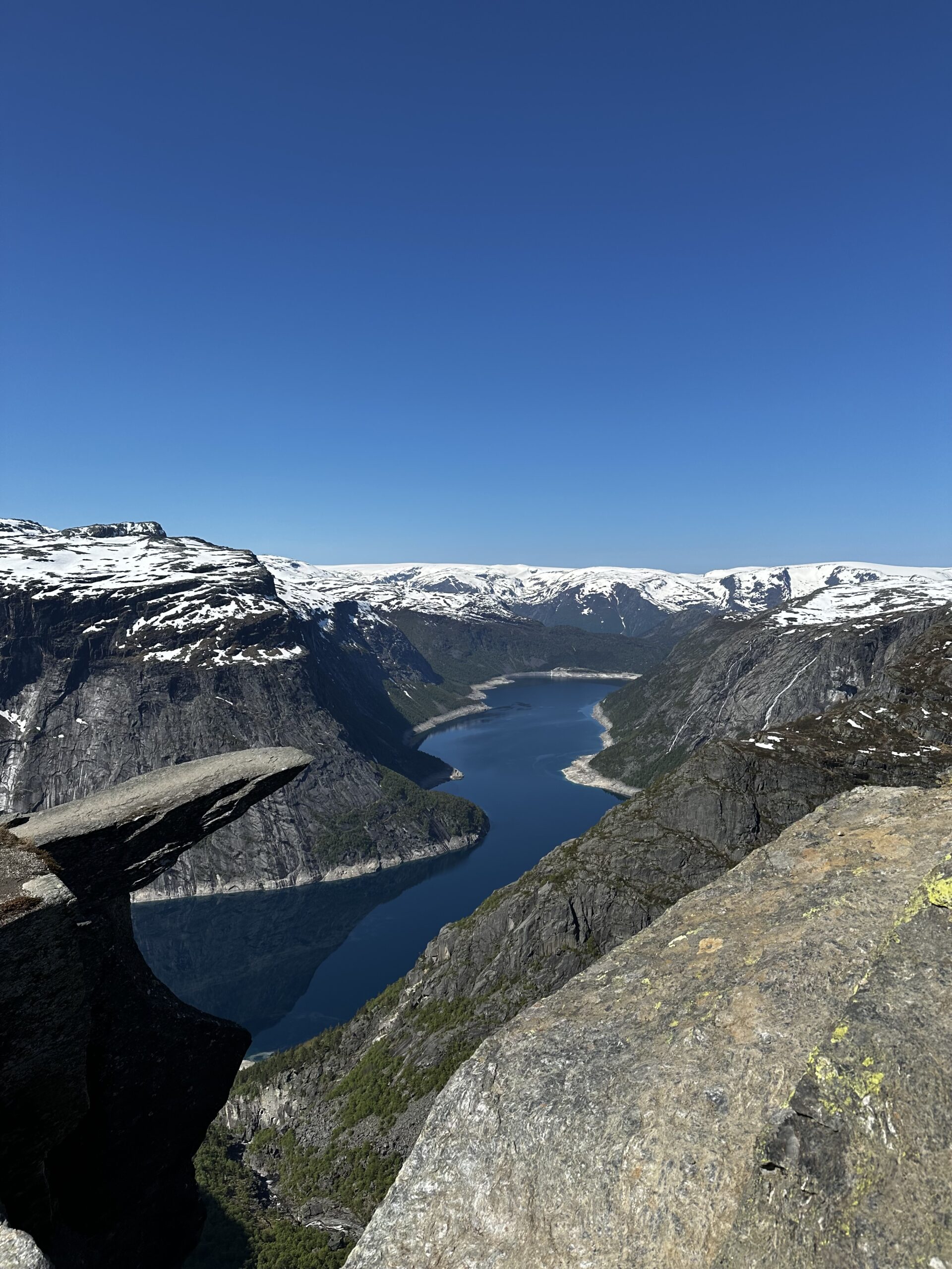 Cliff edge 2500 feet above Lake Ringedalsvatnet Norway with snowcapped mountains in the background